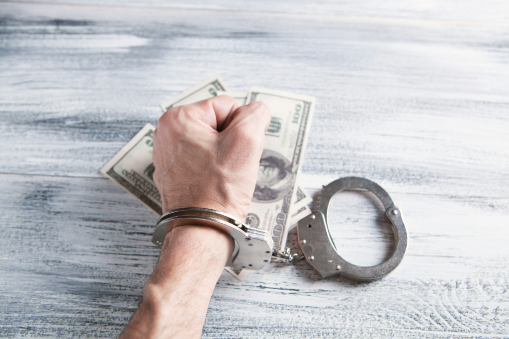 A hand in handcuffs place don top of 100 US dollar banknotes