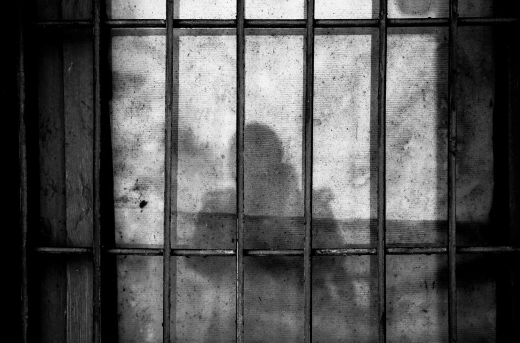 A shadow of a person behind bars