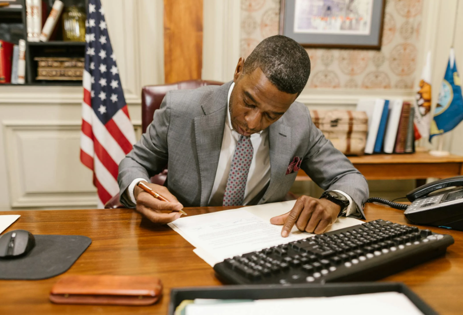 This image shows a man signing a document.