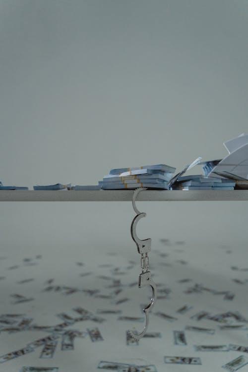 Stacks of cash on a shelf beside handcuffs representing the financial reality of bail in North Carolina