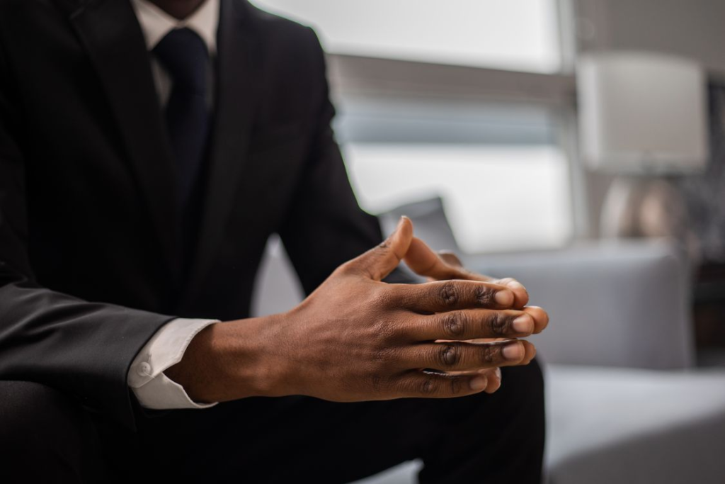 An image of a person sitting with their hands together