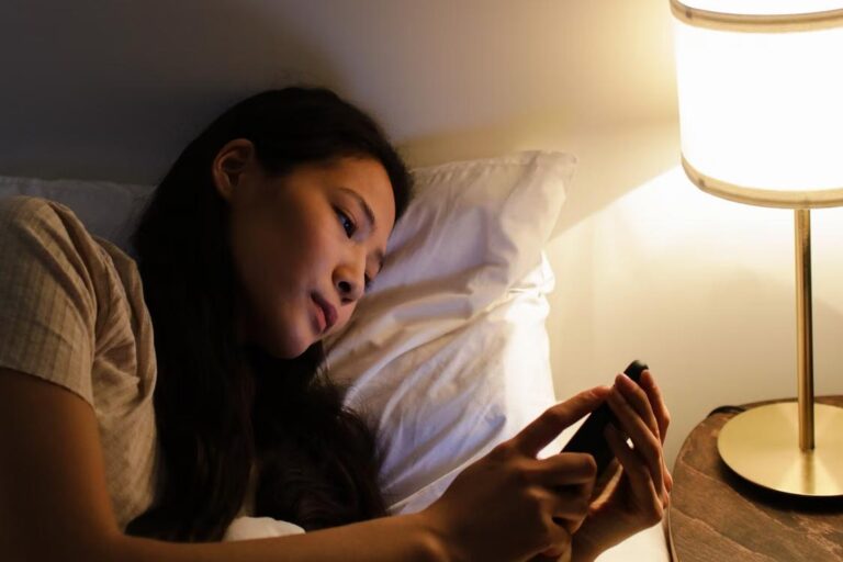 Woman lying in bed using her phone during a late-night call about an emergency bail situation.